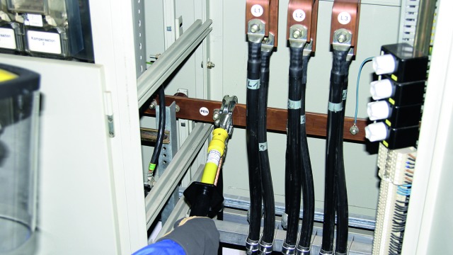 Attaching an earthing and short-circuiting device in a low-voltage switchgear installation using an earthing handle.