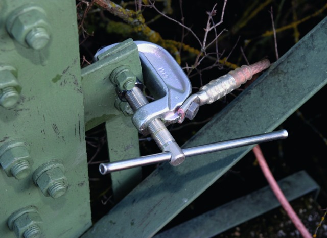 Earth milling clamp attached to a varnished steel mast.